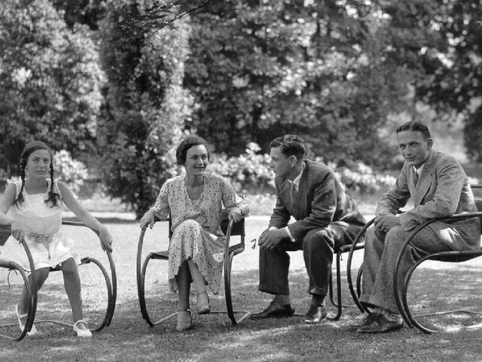 Historische schwarz-weiß Fotografie. Die vier Kinder von Victor und Sophie von Klemperer sitzen in einer Reihe auf Stühlen im Garten.