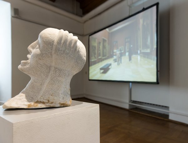 Erika Harborts Skulptur &quot;Schrei&quot; (2022) in den Ausstellungsräumen in Glauchau. Im Hintergrund läuft Marcel Odenbachs IM SCHIFFBRUCH NICHT SCHWIMMEN KÖNNEN (2011) auf einer Leinwand