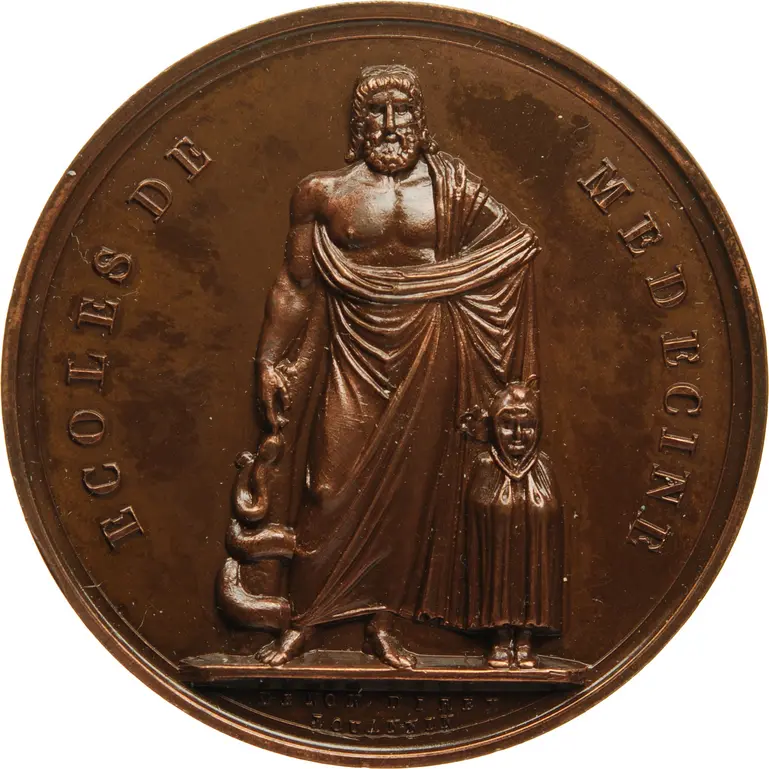 [Translate to English:] Bronze medal, the relief of which shows the holy Asclepius. On the right he holds a large, almost club-like staff towards the ground, with the snake coiling around it (Asclepius' or Asclepius' staff), in front of his left stands the small Telesphoros with hood and cape. The inscription reads: "ECOLES DE MEDECINE".