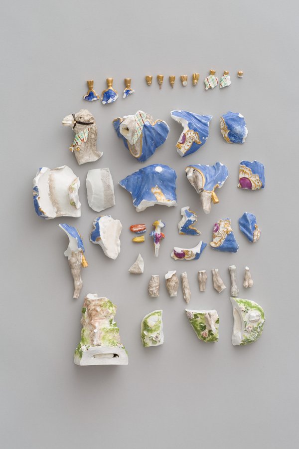 Aufnahme von Bruchteilen eines Porzellanobjektes. Die Stücke sind weiß, blau, gold, grün, beige und lila lackiert.