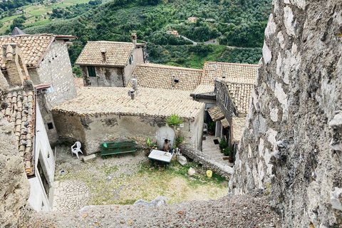 Blick von oben in einen Hinterhof in Olevano, der Blick lässt erkennen, wie steil der Berg ist an den die Gemeinde gebaut wurde, der Verfall des Gemäuers zeigt ihr Alter. Ein Mann sitzt an einem Plastiktisch vor einem Teller mit Obst.