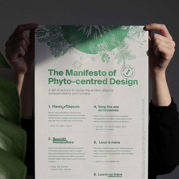 Zwei Hände halten eine Poster-große Druckversion des Manifests neben einer Pflanze.