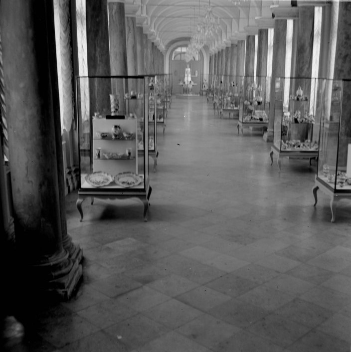 Schwarzweißfotografie. Historische Aufnahme eines langen Raum im Dresdner Zwinger. Zu beiden Seiten befinden sich Vitrinen mit Porzellan.