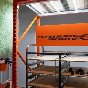 Eine 3D-Druckstation mit einigen gedruckten Kilimandscharo-Spitzen und einem großen Schild auf dem "Skrupel" steht, das moralisch begründete Hemmungen meint und sich vom lateinischen scrupulus (spitzes Steinchen) ableitet.