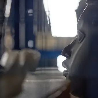 Eine Benin-Maske ist im Profil zu sehen, das Depot in dem sie gelagert ist, liegt in der Unschärfe