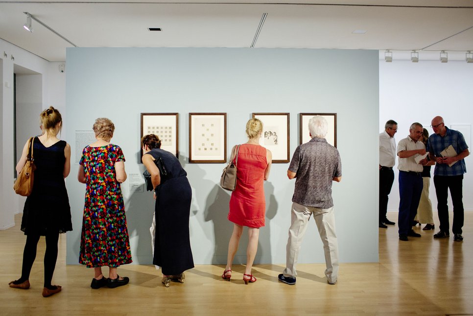 Besucher betrachten Fotos an der Wand