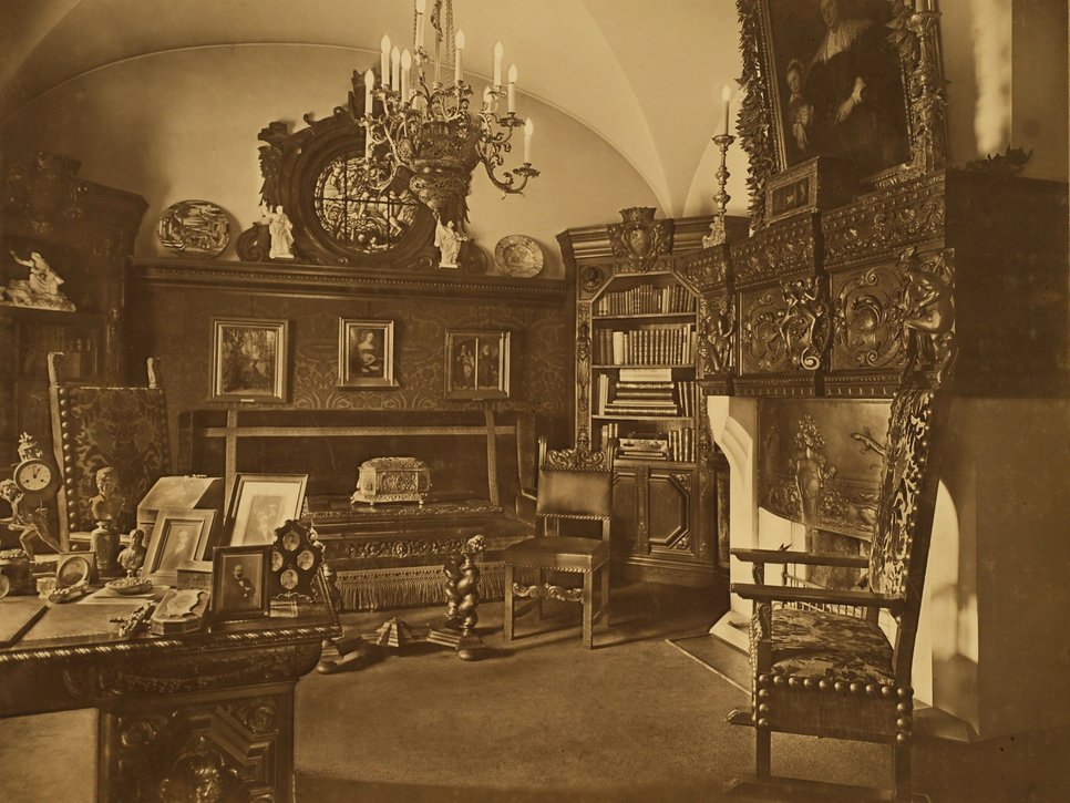 Sepiafotografie. Innenaufnahme des Arbeitszimmers in der Wiener Straße 25. Im Raum stehen opulente historische Möbel. Die Wände sind mit Gemälden verziert.